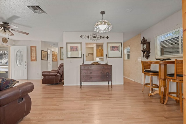 sitting room featuring light hardwood / wood-style floors, a textured ceiling, and ceiling fan