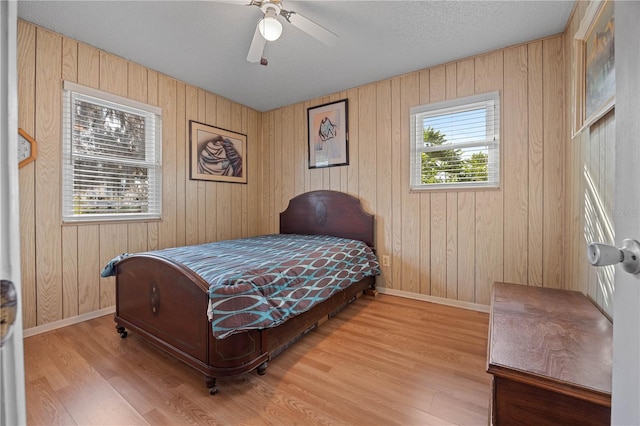 bedroom with ceiling fan, light hardwood / wood-style flooring, and multiple windows