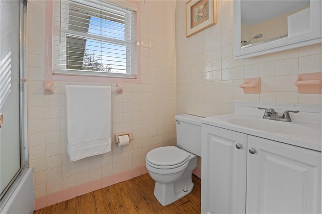 full bathroom featuring vanity, combined bath / shower with glass door, tile walls, and wood-type flooring