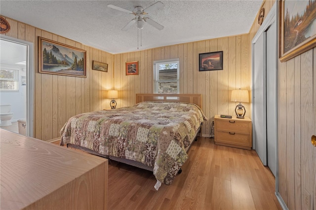 bedroom featuring ceiling fan, a textured ceiling, and wooden walls