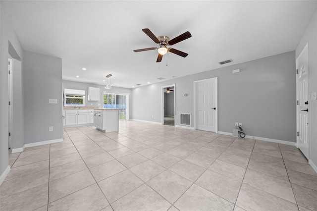 unfurnished living room with ceiling fan, light tile patterned flooring, and sink