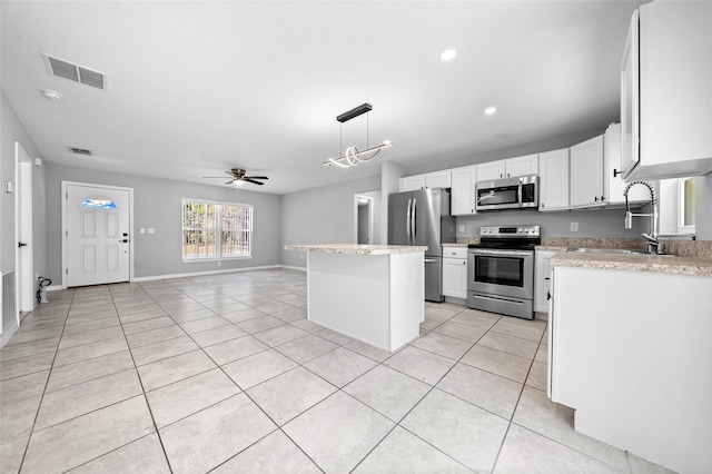 kitchen with appliances with stainless steel finishes, hanging light fixtures, a kitchen island, white cabinets, and sink