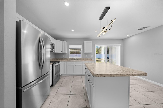 kitchen with light tile patterned floors, stainless steel appliances, decorative light fixtures, a kitchen island, and white cabinets