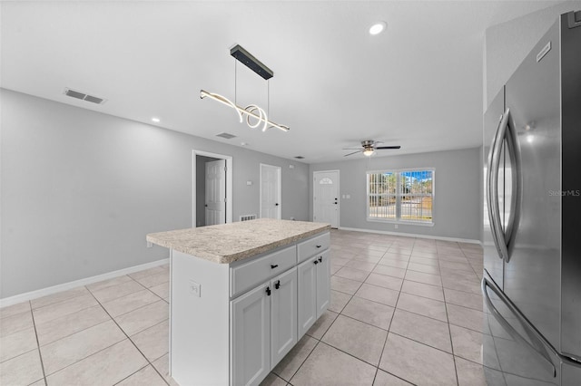 kitchen with a kitchen island, decorative light fixtures, white cabinetry, stainless steel refrigerator, and light tile patterned floors