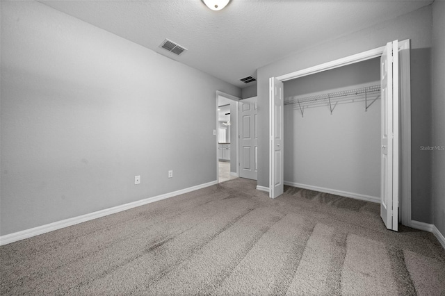 unfurnished bedroom with a textured ceiling, a closet, and carpet floors