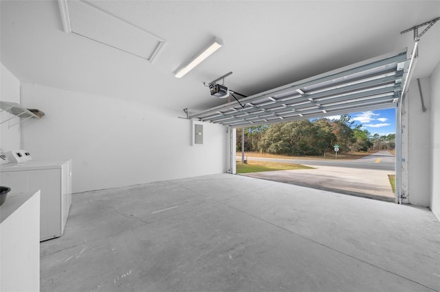 garage with a garage door opener, independent washer and dryer, and electric panel