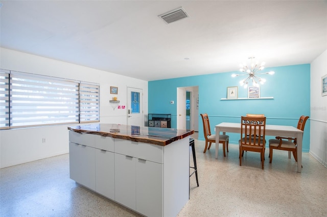 kitchen featuring white cabinets, a center island, a chandelier, and a kitchen bar