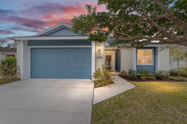 ranch-style home with an attached garage, driveway, a lawn, and stucco siding