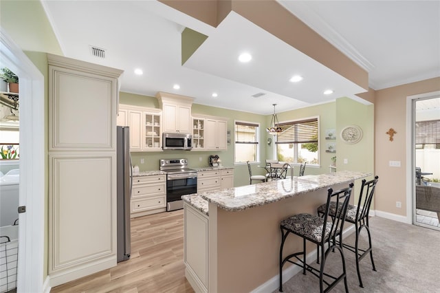 kitchen featuring a center island, hanging light fixtures, a kitchen breakfast bar, stainless steel appliances, and light stone countertops