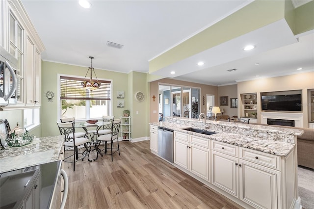 kitchen featuring sink, light hardwood / wood-style flooring, a kitchen island, decorative light fixtures, and stainless steel dishwasher