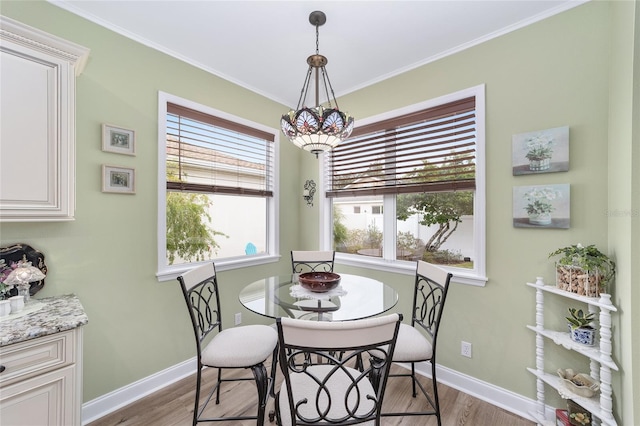 dining area with ornamental molding and light hardwood / wood-style flooring