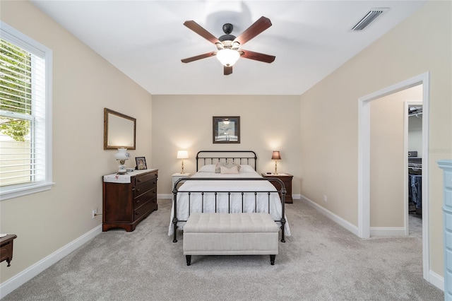 carpeted bedroom with a walk in closet and ceiling fan