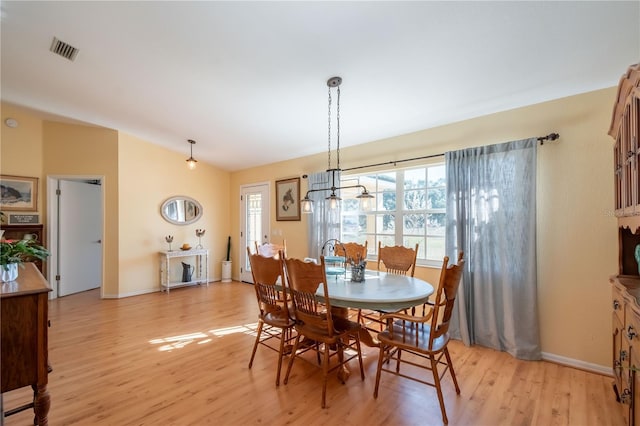 dining space with vaulted ceiling and light wood-type flooring