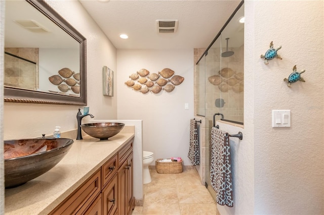 bathroom featuring a shower with door, vanity, a textured ceiling, and toilet