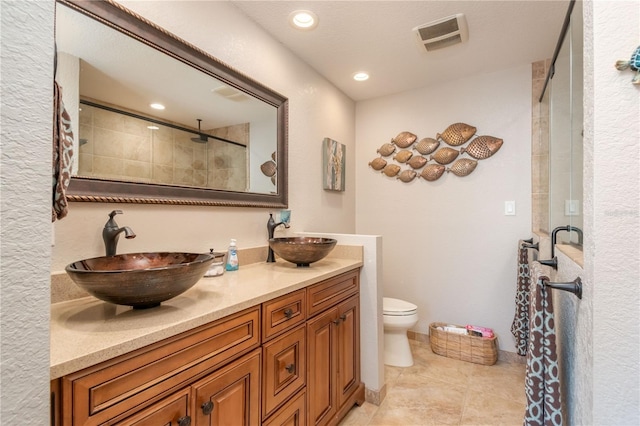 bathroom featuring tile patterned flooring, vanity, tiled shower, and toilet