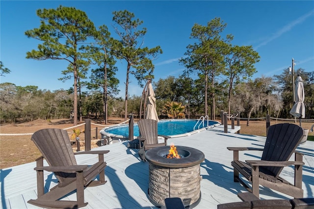 view of pool featuring a wooden deck and an outdoor fire pit