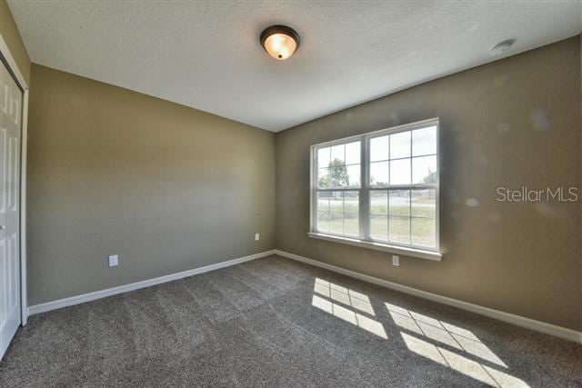 unfurnished room with dark carpet