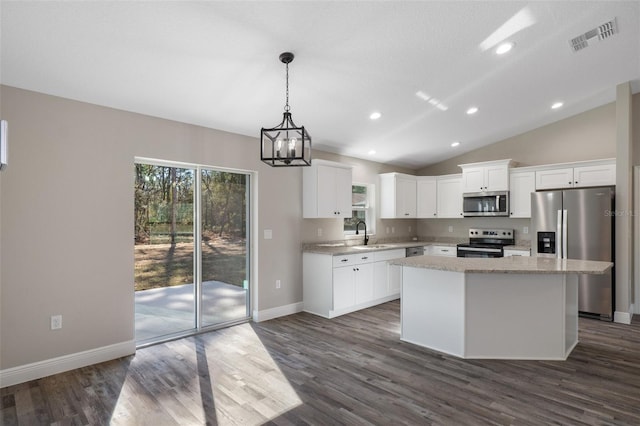 kitchen with pendant lighting, appliances with stainless steel finishes, dark hardwood / wood-style floors, white cabinets, and a kitchen island