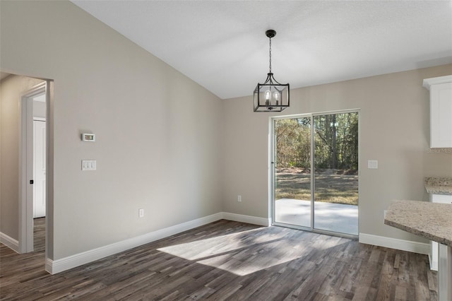 unfurnished dining area with a notable chandelier and dark wood-type flooring