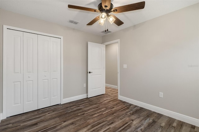 unfurnished bedroom featuring ceiling fan, dark hardwood / wood-style flooring, and a closet