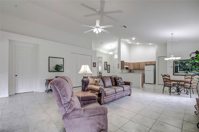 living room with light tile patterned flooring, ceiling fan with notable chandelier, and high vaulted ceiling