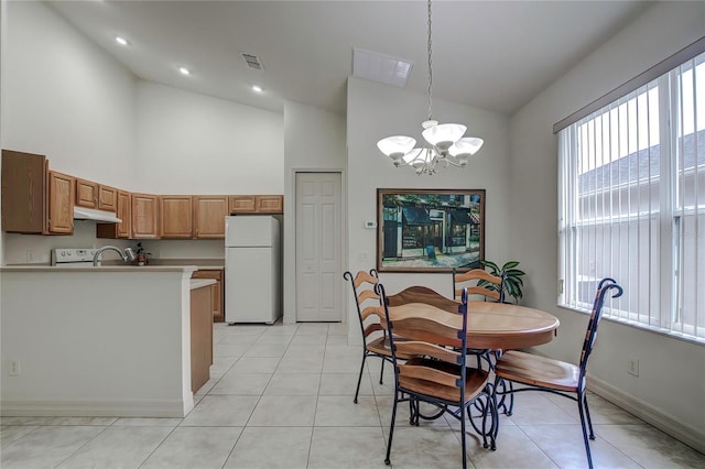 dining space with sink, high vaulted ceiling, an inviting chandelier, and light tile patterned flooring