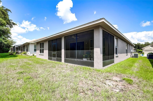 rear view of property with a sunroom, central AC unit, and a yard