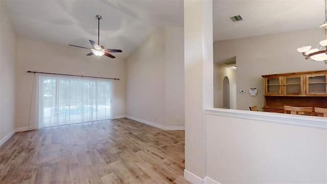 unfurnished living room with ceiling fan with notable chandelier, light hardwood / wood-style flooring, and lofted ceiling