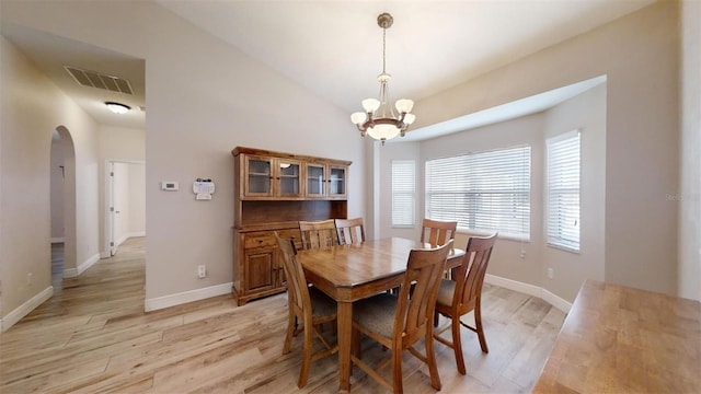 dining space with light wood-type flooring, a chandelier, and lofted ceiling