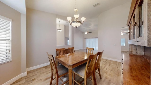 dining room with light wood-type flooring, ceiling fan with notable chandelier, and a healthy amount of sunlight