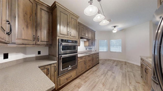 kitchen with stainless steel appliances, hanging light fixtures, and light hardwood / wood-style floors