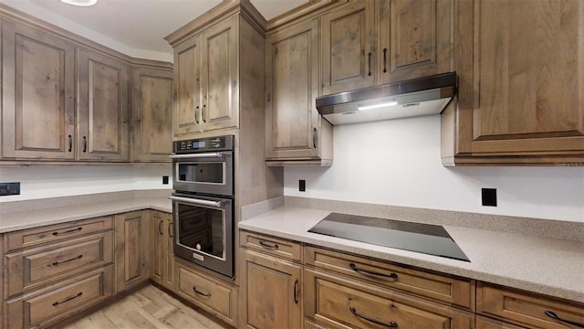 kitchen featuring black electric cooktop, light hardwood / wood-style floors, and double oven