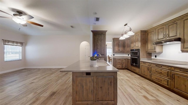 kitchen with pendant lighting, black appliances, a kitchen island, light hardwood / wood-style floors, and sink