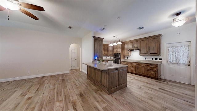 kitchen featuring decorative light fixtures, black appliances, light hardwood / wood-style flooring, and kitchen peninsula