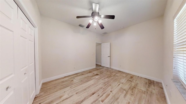 unfurnished bedroom featuring a closet, ceiling fan, light wood-type flooring, and multiple windows