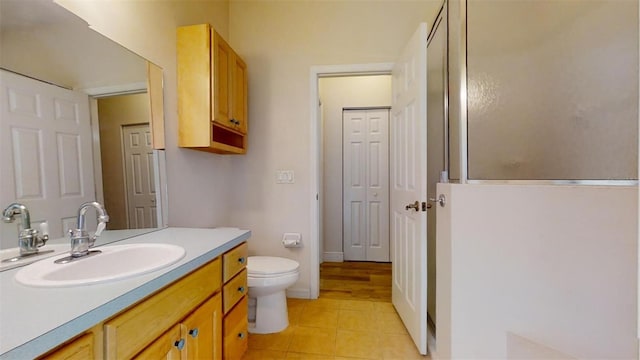 bathroom featuring vanity, toilet, walk in shower, and tile patterned floors