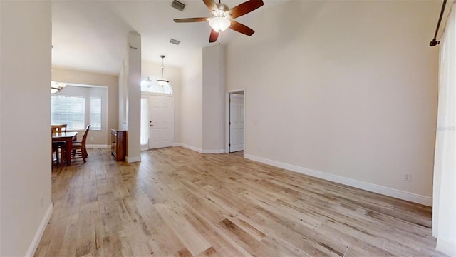 entrance foyer with light wood-type flooring, ceiling fan, and a towering ceiling