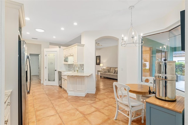 kitchen with decorative light fixtures, backsplash, white cabinetry, stainless steel fridge with ice dispenser, and light tile patterned floors