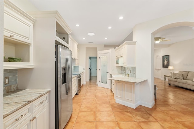 kitchen with ceiling fan, backsplash, appliances with stainless steel finishes, and light tile patterned flooring