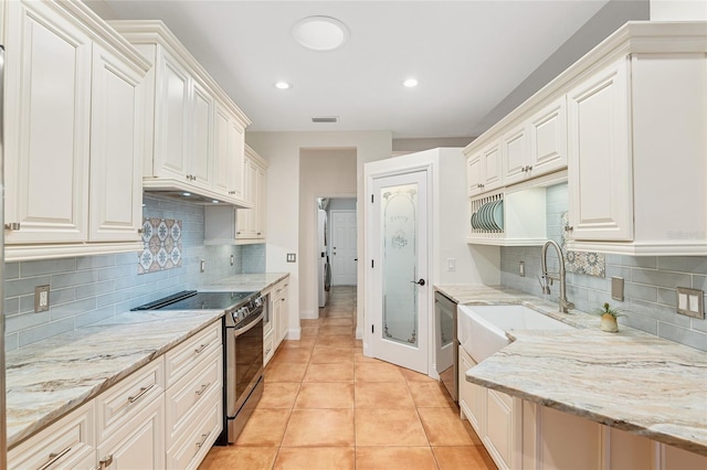 kitchen featuring light stone countertops, light tile patterned floors, electric range, and white cabinets