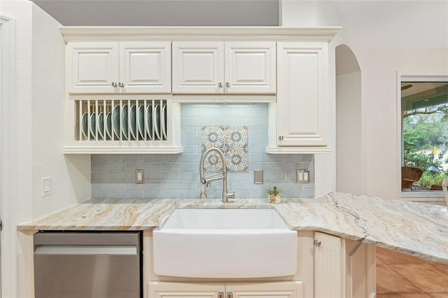 kitchen featuring sink, stainless steel dishwasher, light stone countertops, and tasteful backsplash