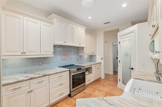 kitchen featuring decorative backsplash, light stone countertops, light tile patterned floors, and stainless steel electric range oven