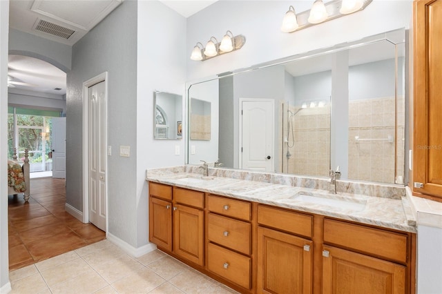 bathroom featuring vanity, a tile shower, and tile patterned flooring