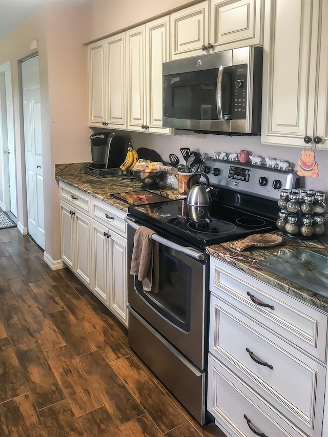 kitchen with dark stone countertops, dark wood finished floors, white cabinetry, appliances with stainless steel finishes, and baseboards