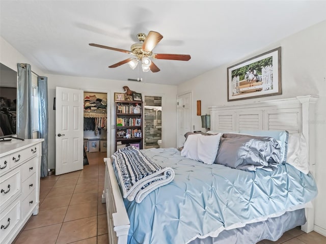 bedroom with a spacious closet, light tile patterned flooring, a ceiling fan, and a closet