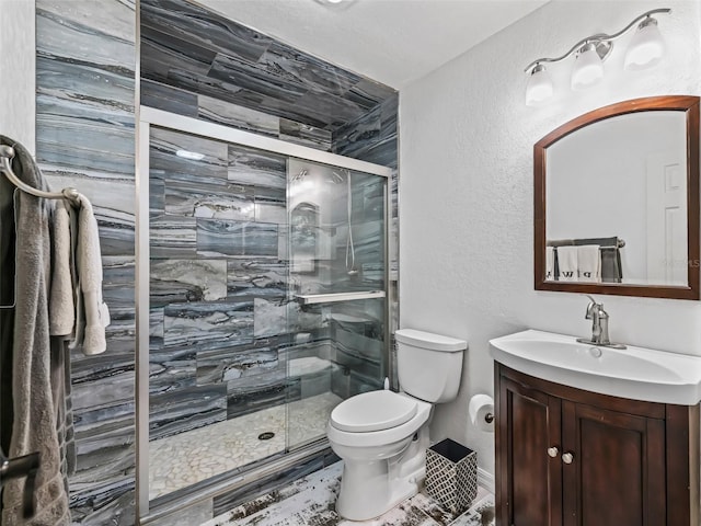 bathroom with vanity, toilet, a shower stall, and a textured wall