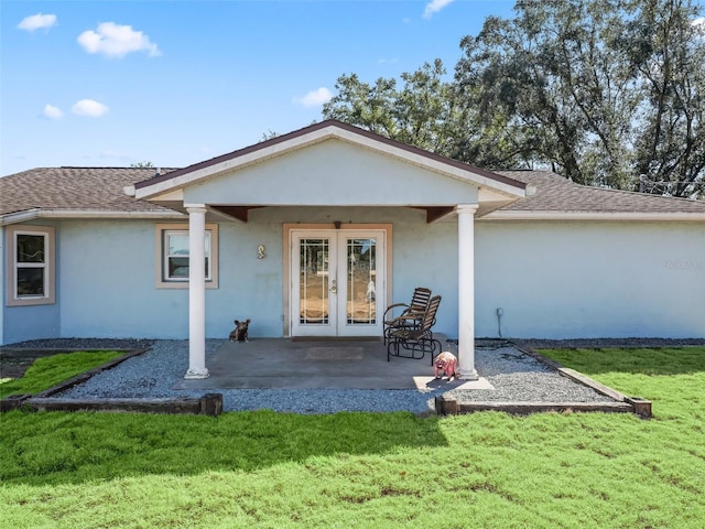 back of house with french doors, a lawn, roof with shingles, and stucco siding