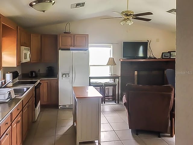 kitchen with light tile patterned floors, electric range, stainless steel microwave, white fridge with ice dispenser, and vaulted ceiling