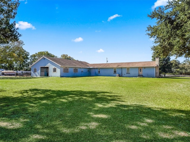 rear view of property featuring a yard, a chimney, and stucco siding