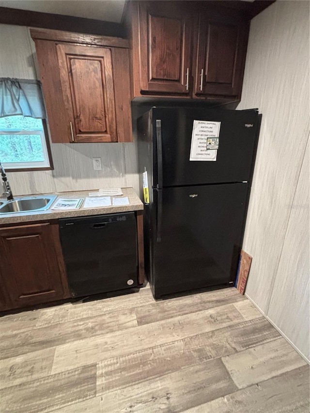 kitchen featuring black appliances, dark brown cabinetry, and sink